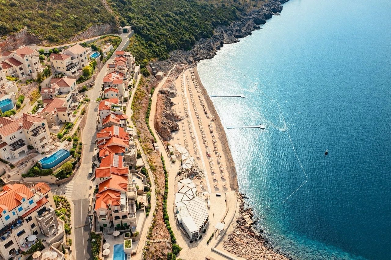 Vue aérienne du complexe de luxe Lustica Bay à Radovići, Monténégro : plage privée, villas et mer.