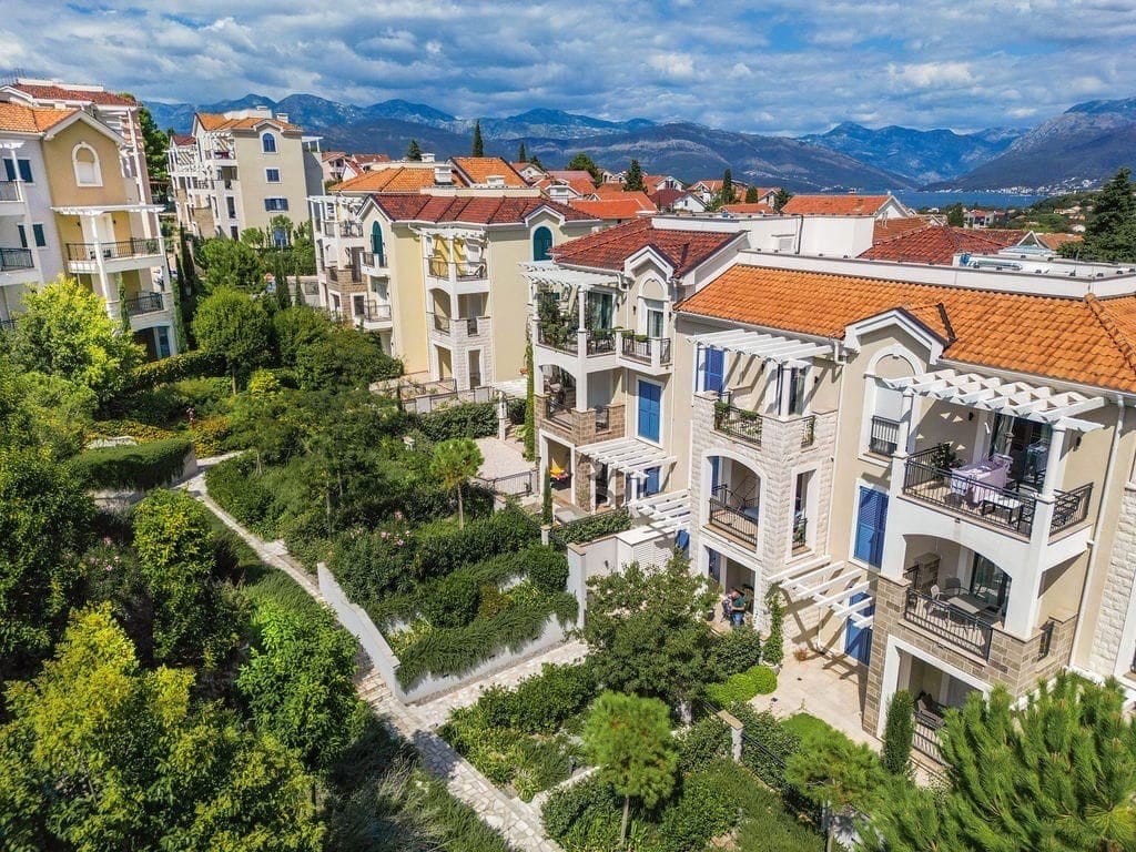 View of the Lustica Bay residential complex in Radovici, Montenegro: modern houses with terraces, gardens, and views of the mountains and the sea.