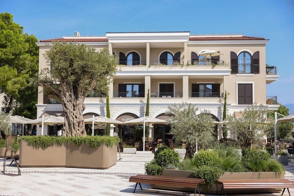 Facade of a residential complex in Luštica Bay, Radovići, Montenegro: modern architecture, terraces, and a summer café terrace.