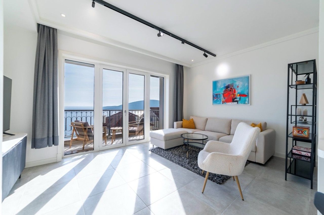 Bright living room in Luštica Bay, Radovići, Montenegro: modern furniture, panoramic sea view, and balcony.