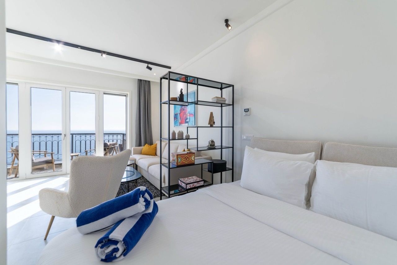 Bedroom in a Lustica Bay apartment, Radovici, Montenegro: double bed, seating area, and sea view from the terrace.