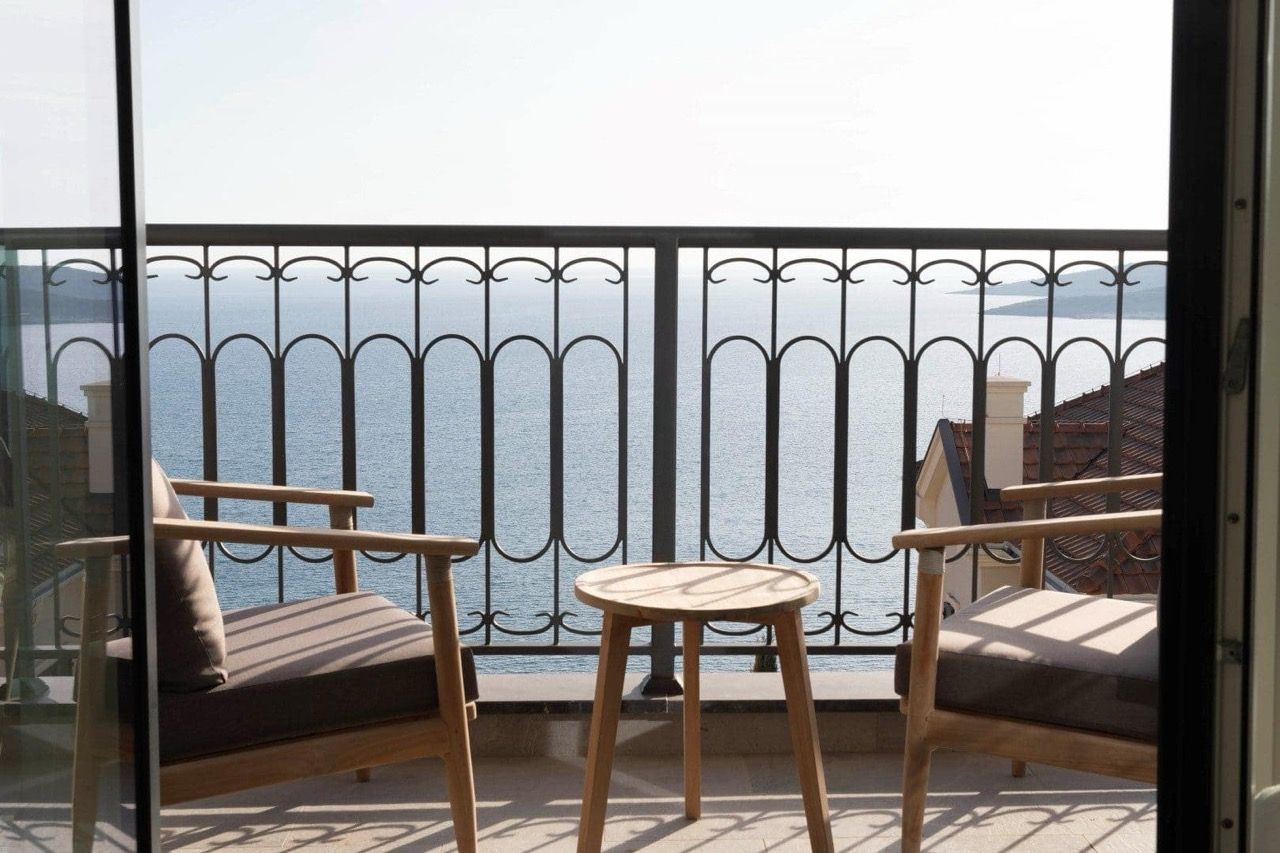 Balcony with wooden chairs and a table overlooking the sea in an apartment in Luštica Bay, Radovići, Montenegro.