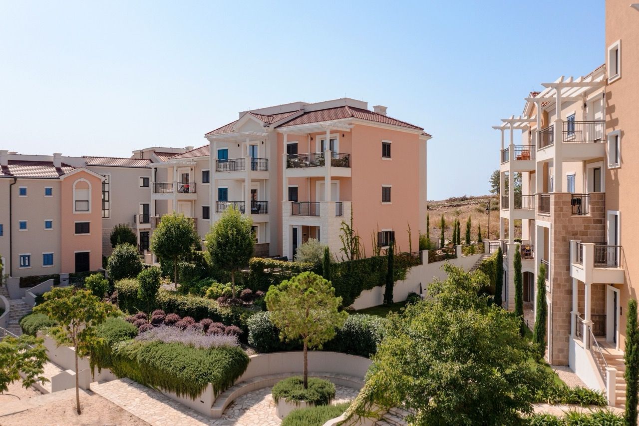 Modern residential buildings in the Luštica Bay complex, Radovići, Montenegro, with landscaped grounds and a garden.
