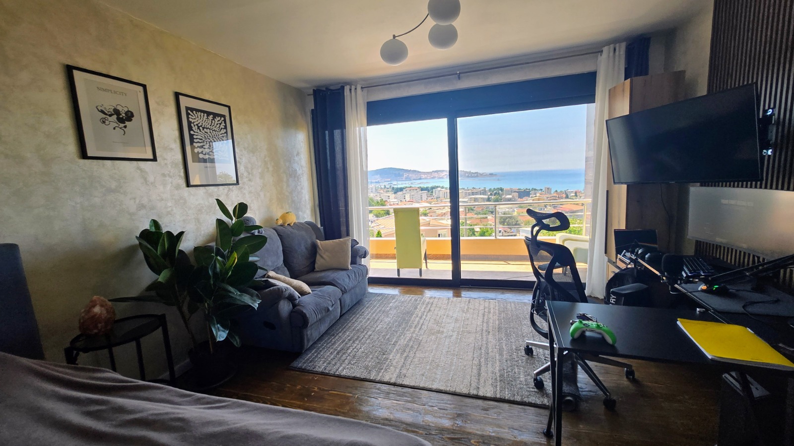 Salon z panoramicznym widokiem na morze w willi w mieście Bar, Czarnogóra: miękka sofa, strefa do pracy i wyjście na taras.
