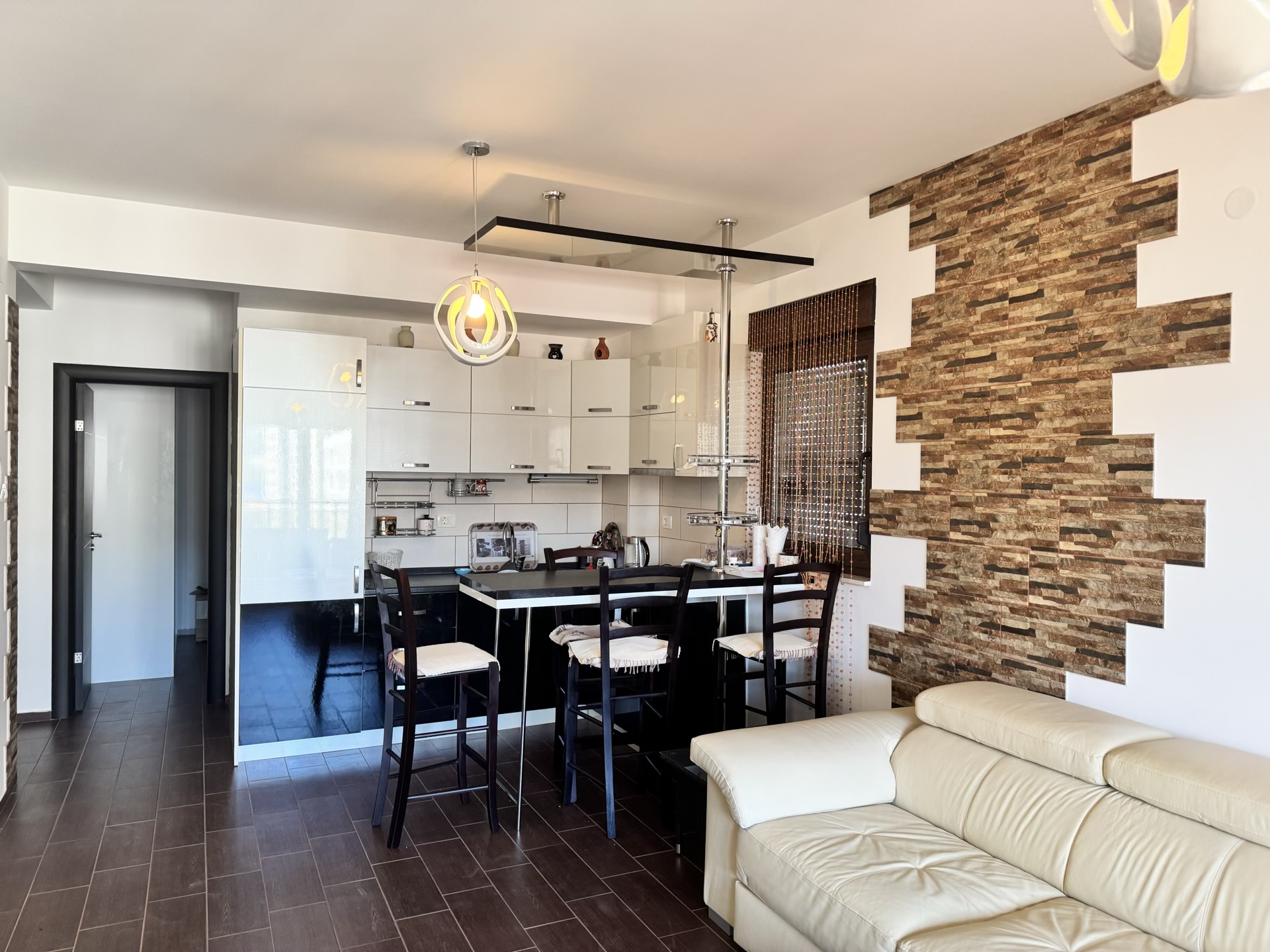 Modern kitchen-living room with a bar counter and stone finishes in an apartment in Budva, Montenegro.