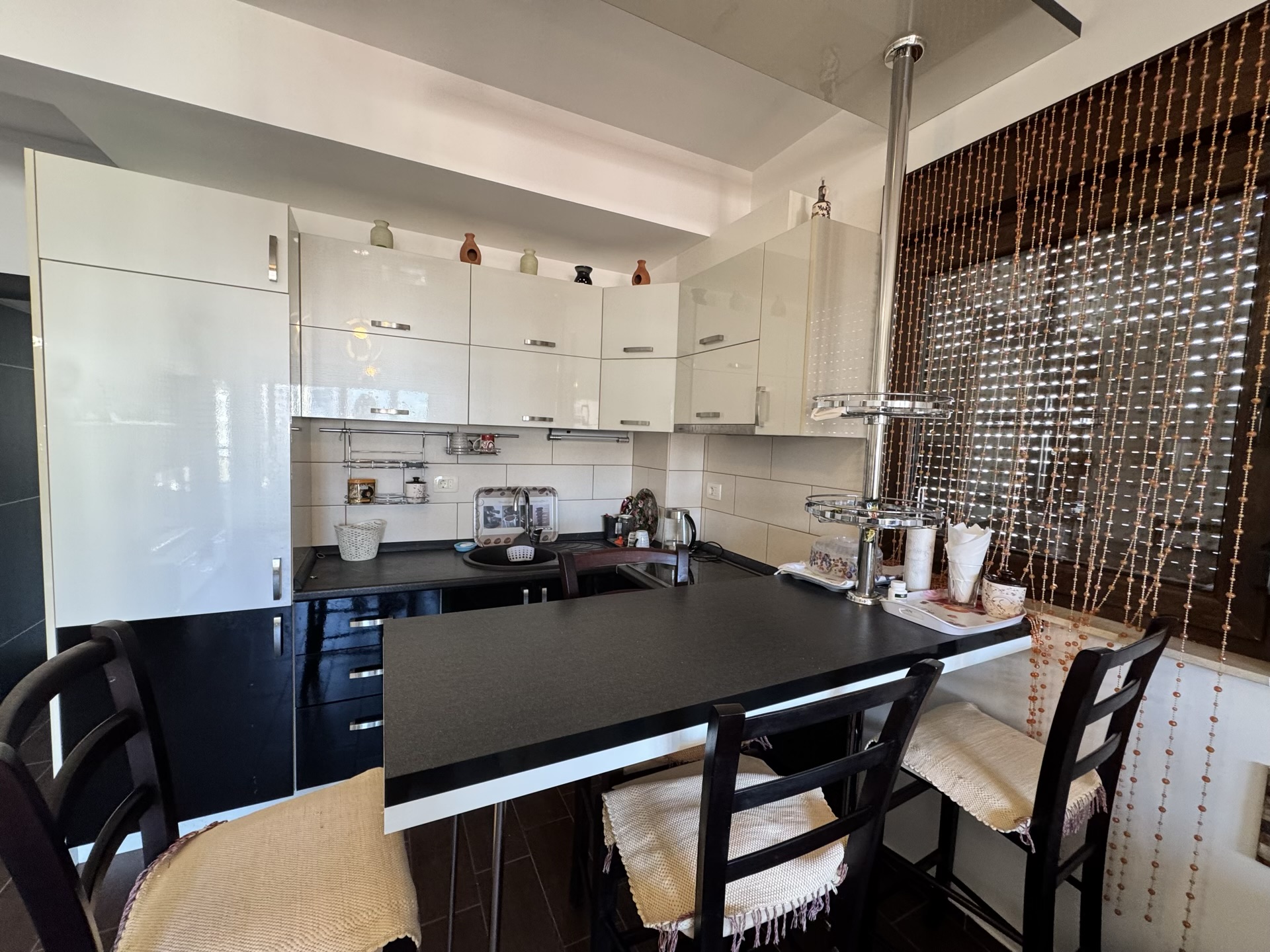 Modern kitchen in an apartment in Budva, Montenegro: black-and-white cabinetry, a bar counter, and chairs in the dining area.