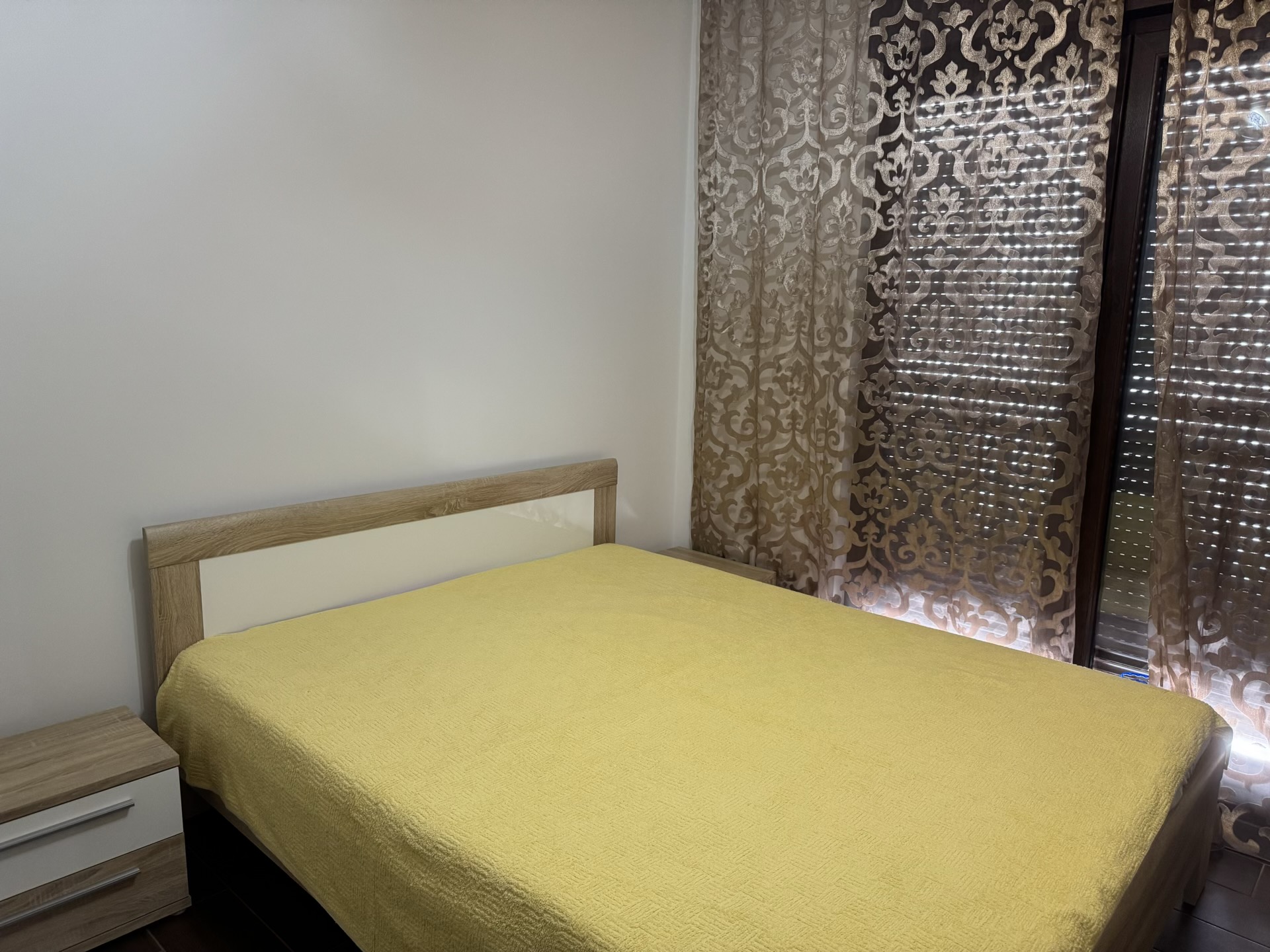 Cozy bedroom with a double bed and bedside table in an apartment in Budva, Montenegro. Window with blackout curtains.