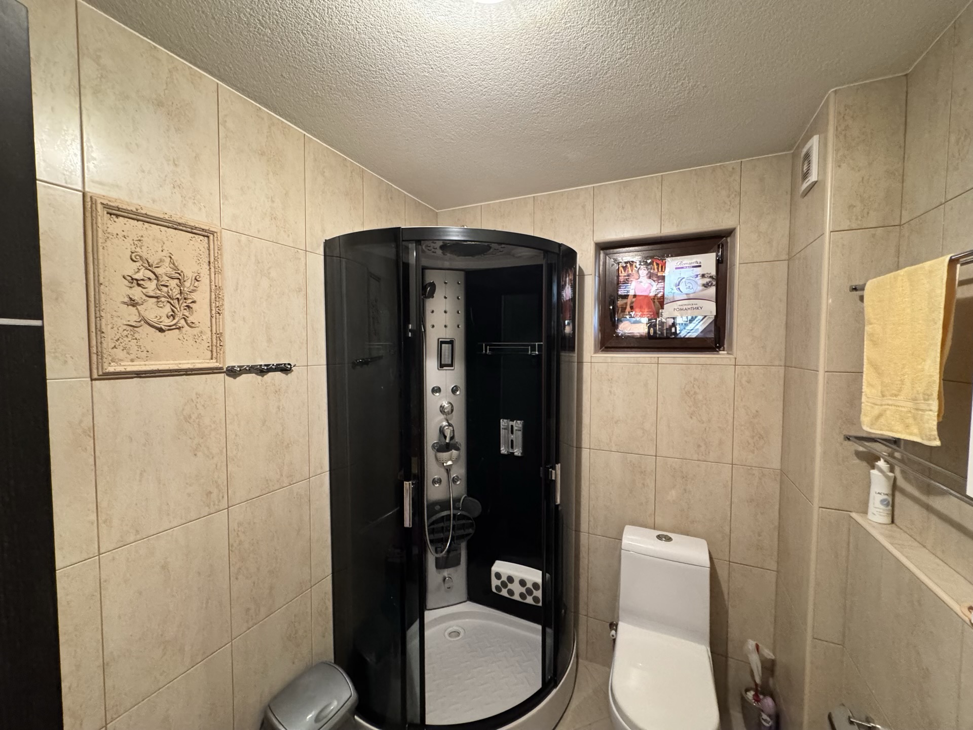 Bathroom in an apartment in Budva, Montenegro: black shower cabin, white sanitary ware, and beige wall tiles.