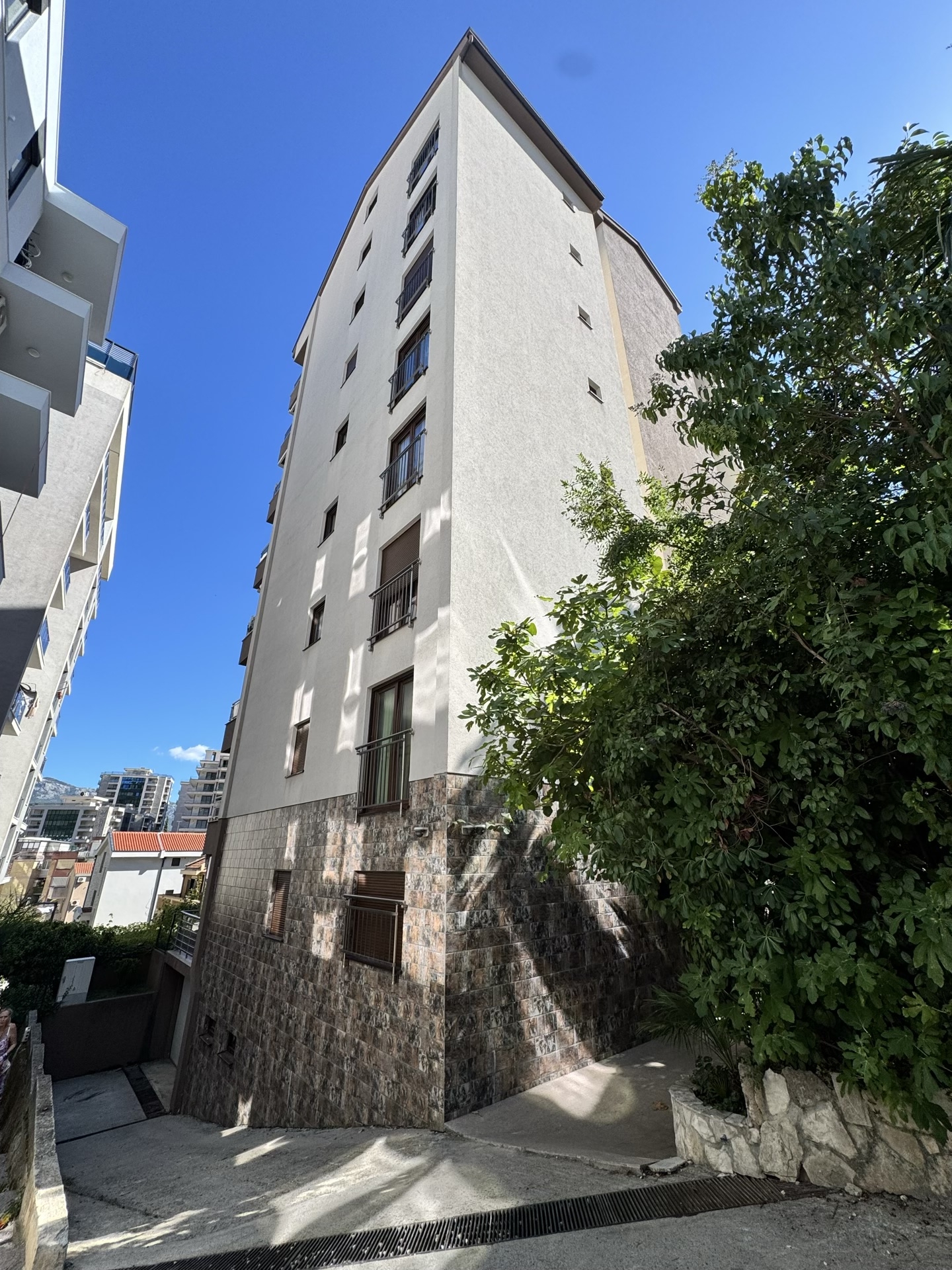 Modern multi-story residential building with stone cladding and balconies in Budva, Montenegro.