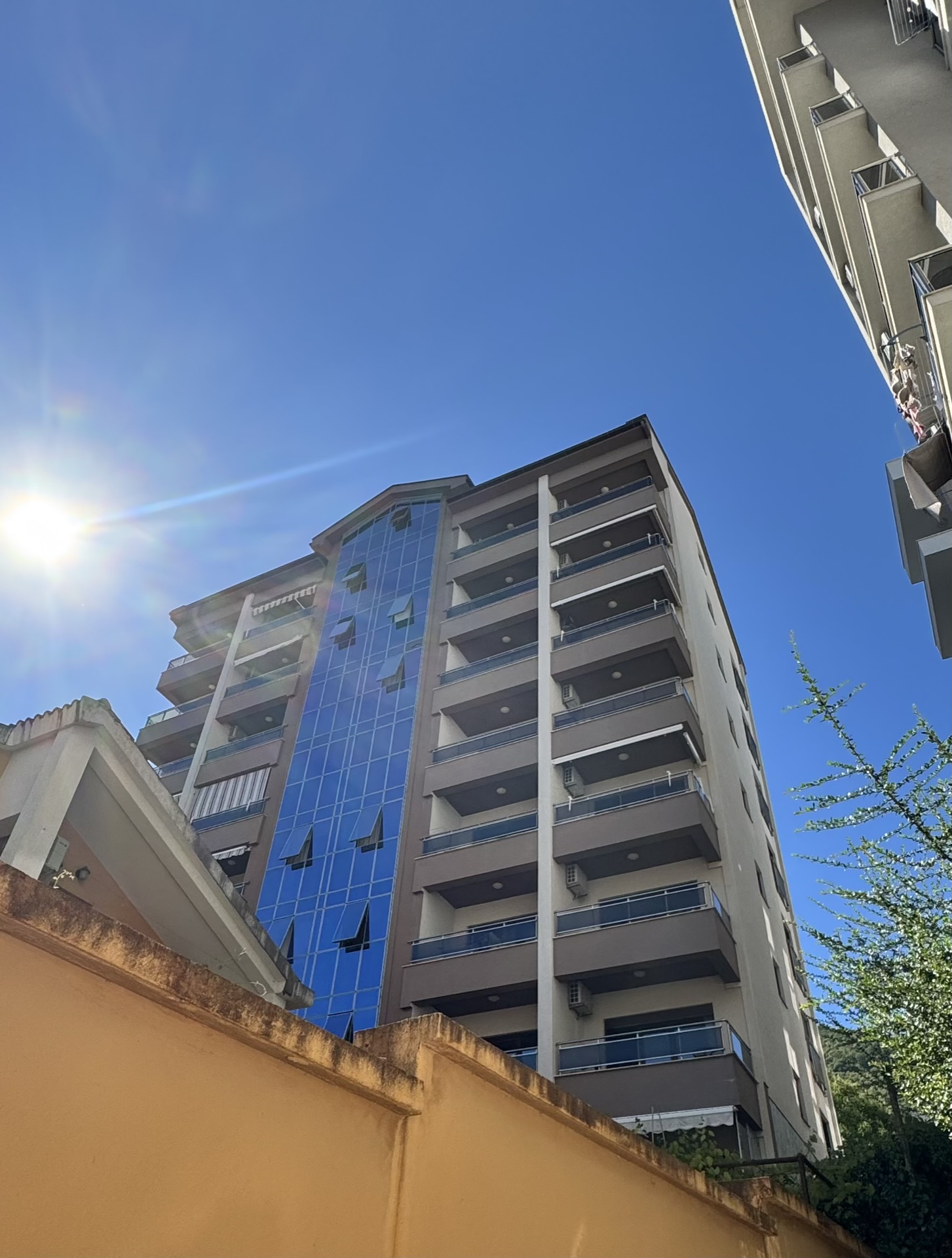Modern multi-story residential building with panoramic glazing and balconies in Budva, Montenegro.