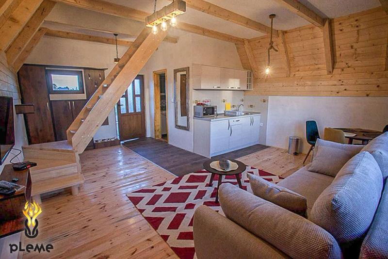 Living room in a wooden house in Žabljak, Montenegro: kitchen, soft sofa, staircase, and natural wood finishes.