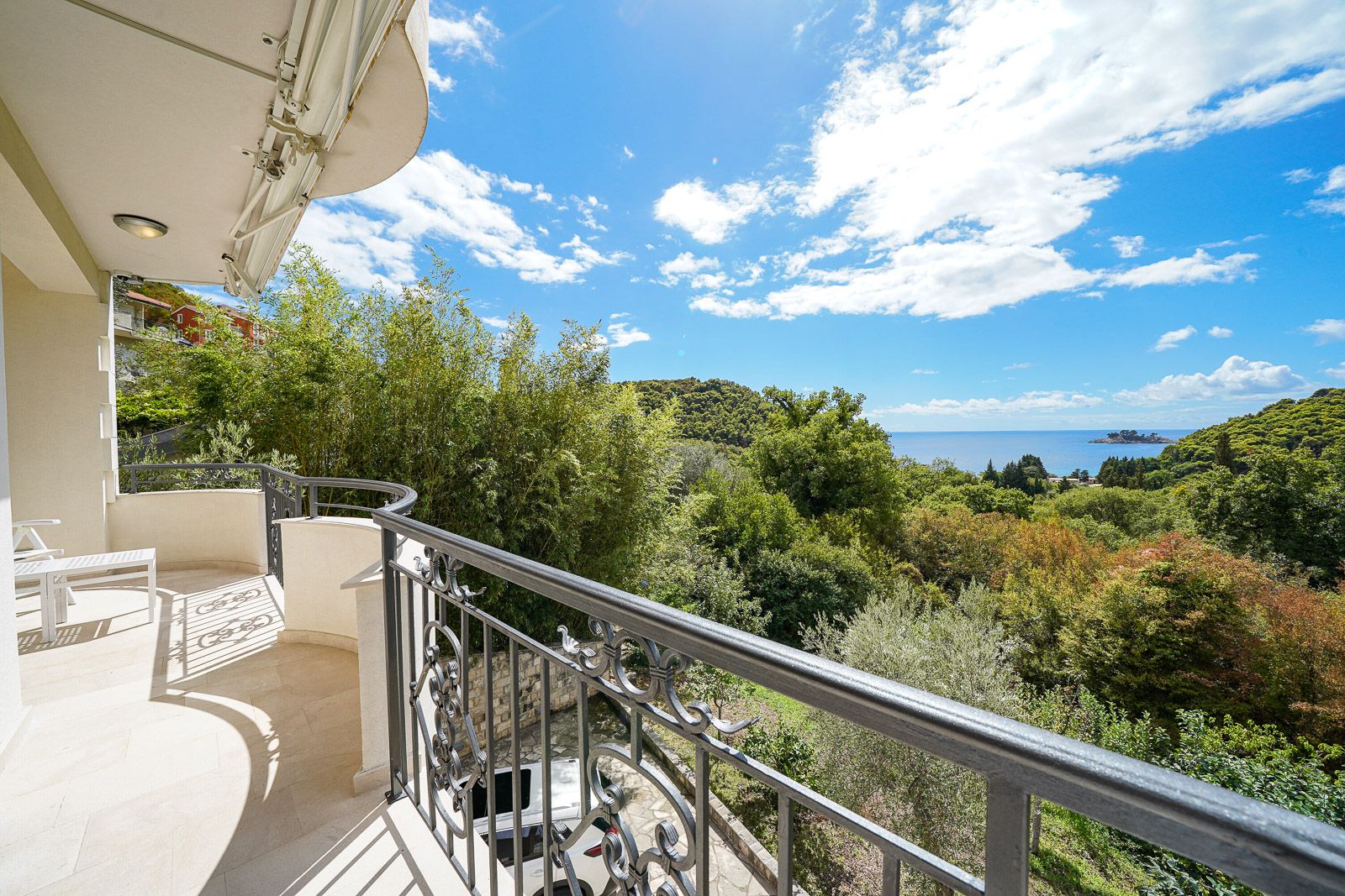 Geräumiger Balkon der Wohnung in Petrovac, Montenegro, mit schmiedeeisernem Geländer und Panoramablick auf das Meer und das Grün.
