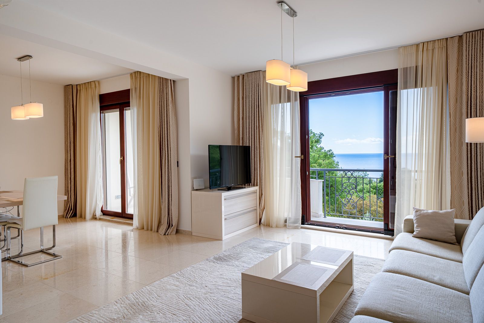 Wohnzimmer mit Meerblick in einer Wohnung in Petrovac, Montenegro: helles Interieur, weiche Möbel und Panoramafenster.