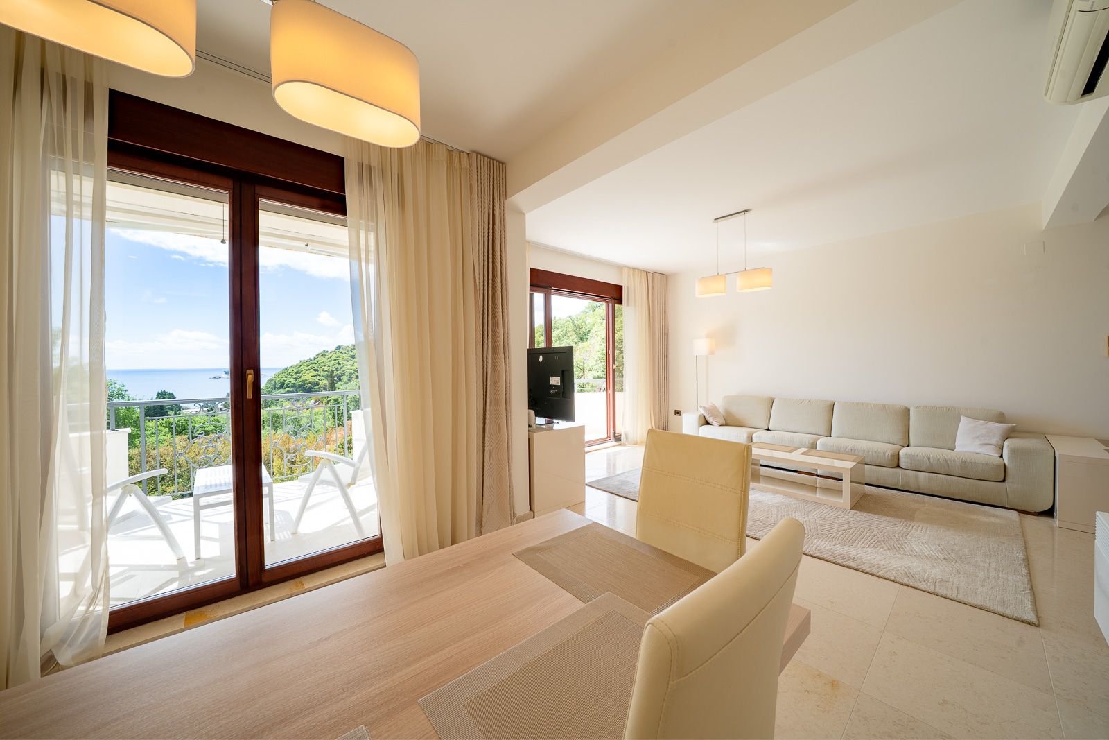 Helles Wohnzimmer mit Meerblick in einer Wohnung in Petrovac, Montenegro: moderne Möbel, Terrasse und Panoramafenster.