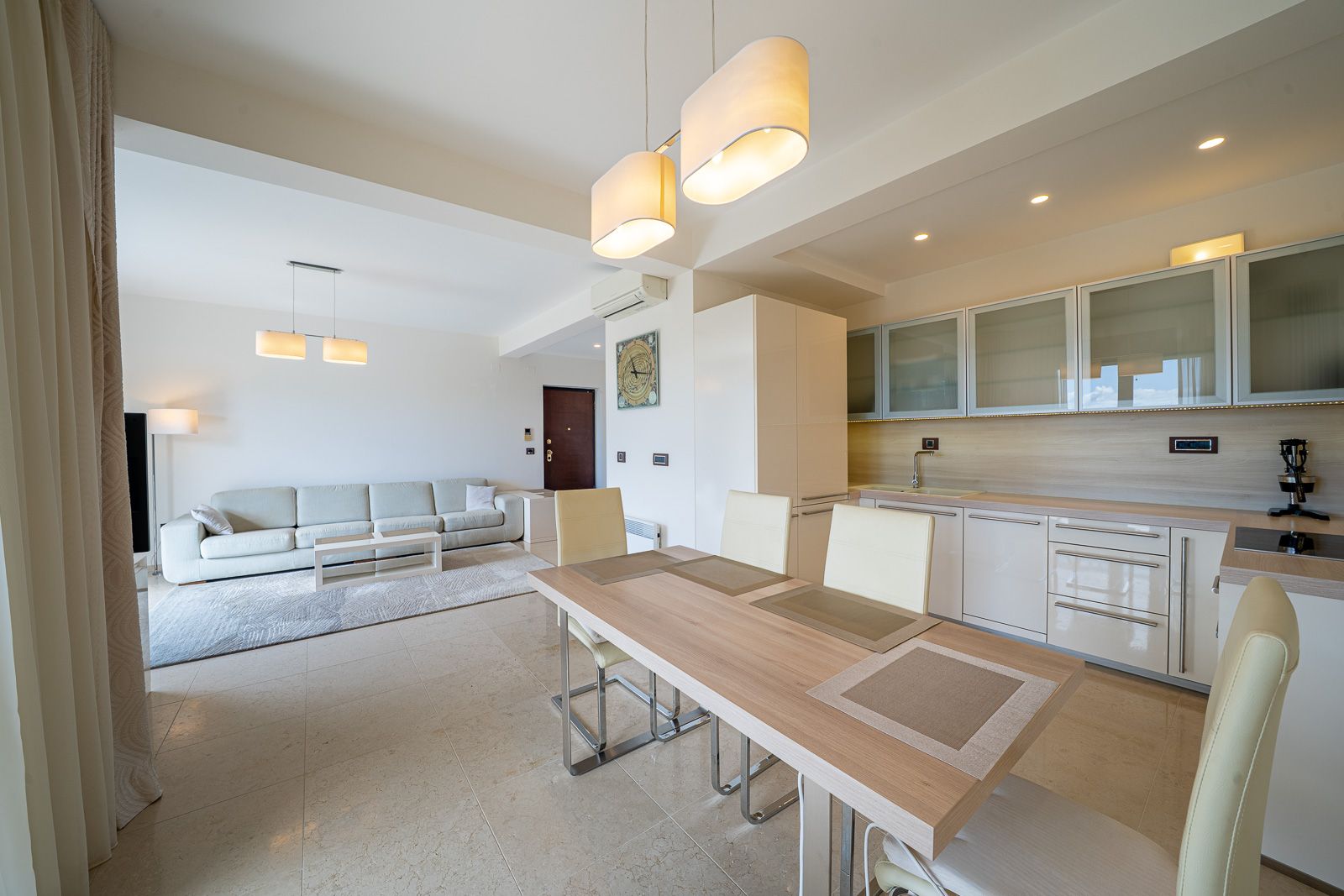 Modernes Wohnzimmer mit Küche in einer Wohnung in Petrovac, Montenegro: helle Möbel, Essbereich und stilvolles Interieur.