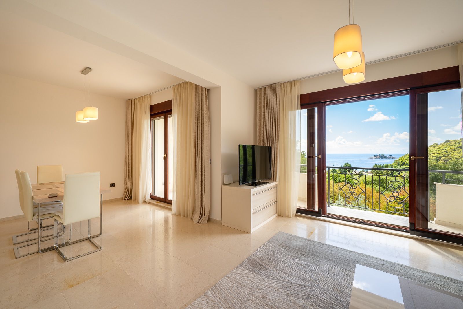 Wohnzimmer mit Essbereich und Panoramablick auf das Meer in einer Wohnung in Petrovac, Montenegro: helles Interieur mit Möbeln.