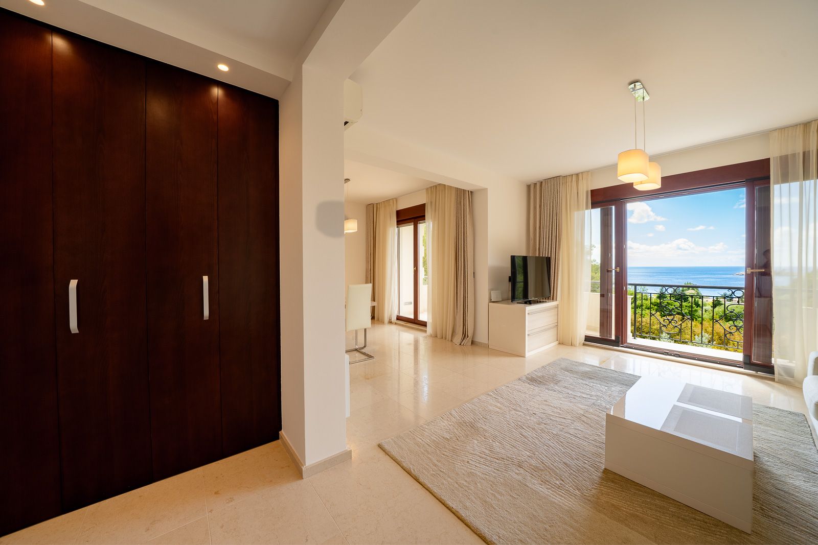 Wohnzimmer mit Panoramablick auf das Meer in einer Wohnung in Petrovac, Montenegro: helles Interieur, Terrasse und Holzmöbel.