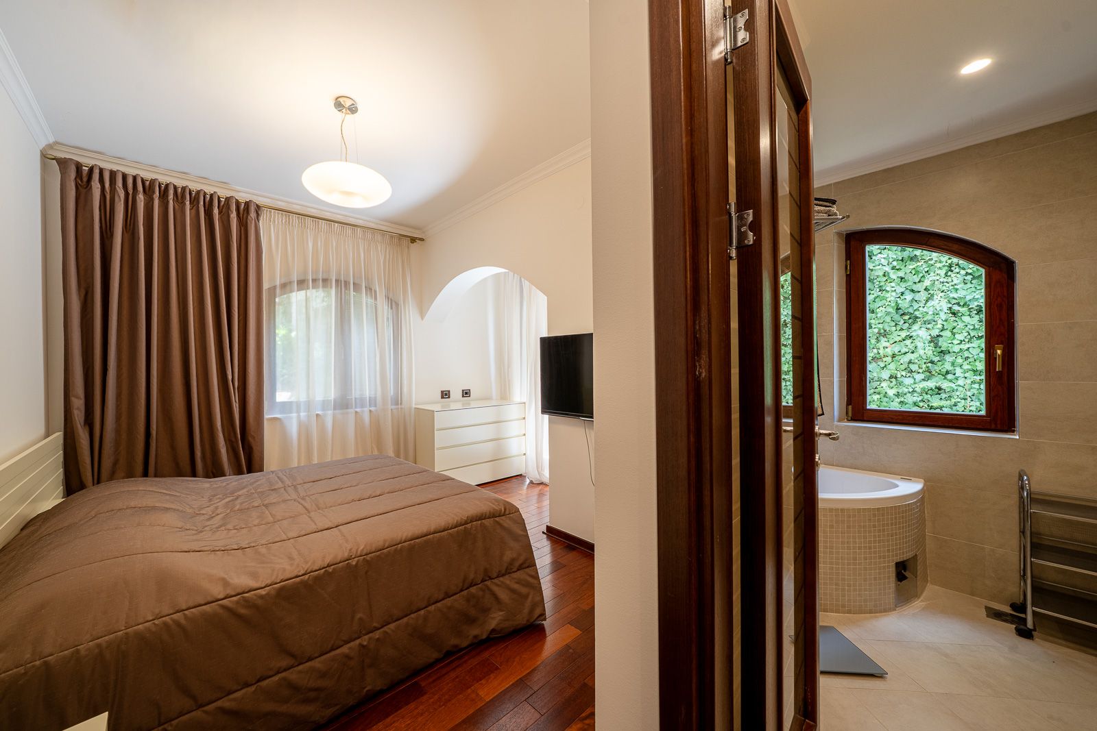 Schlafzimmer mit Doppelbett und Badezimmer in einer Wohnung in Petrovac, Montenegro: modernes Interieur und Blick auf den Garten.