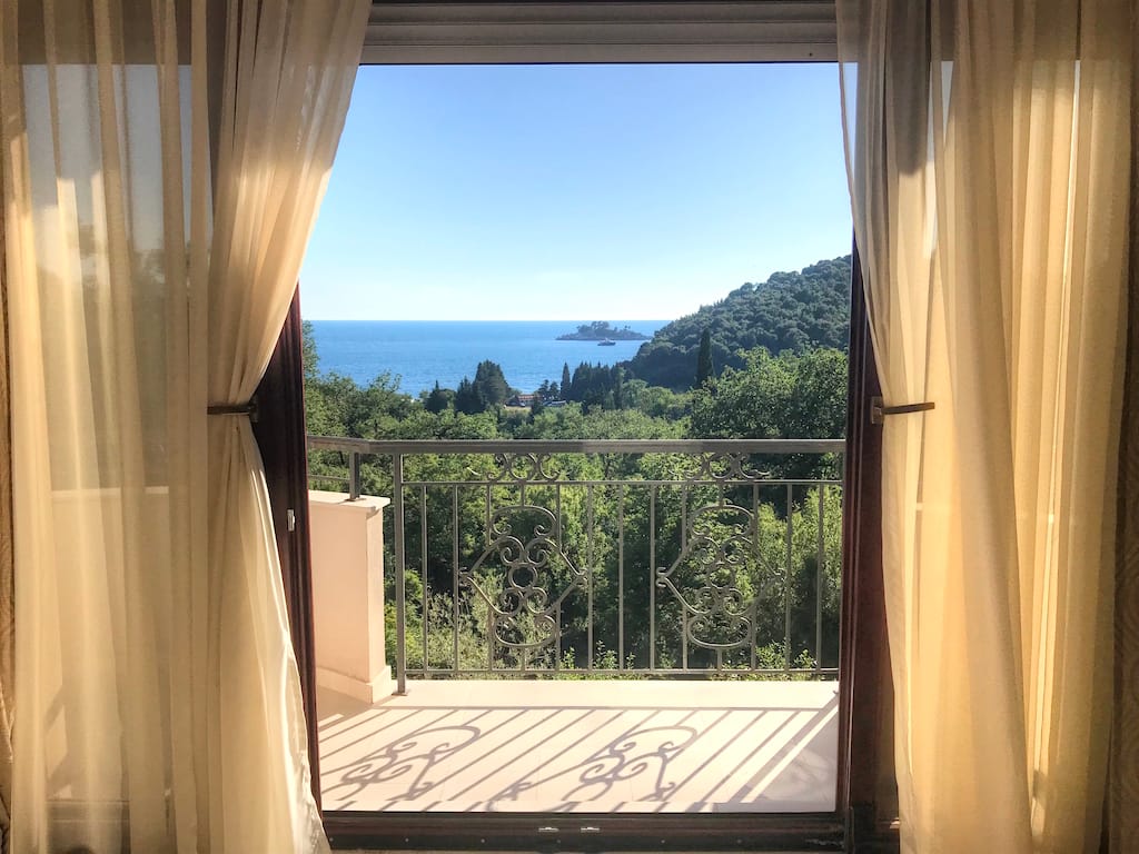 Blick vom Balkon der Wohnung in Petrovac, Montenegro: Panorama von Meer, Inseln und Grün durch ein schmiedeeisernes Geländer.