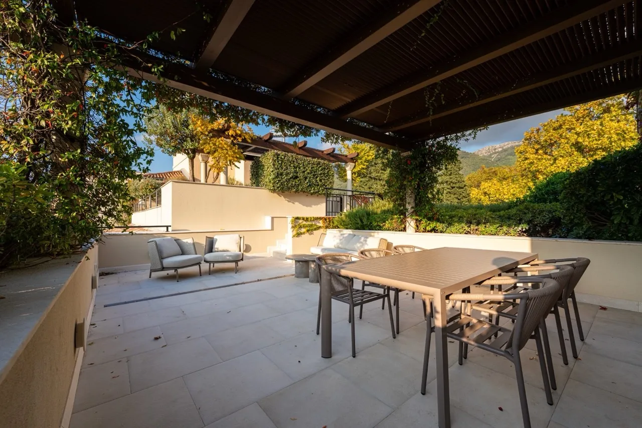 Terrasse mit Gartenmöbeln und Überdachung in der Wohnung Porto Montenegro, Tivat, Montenegro. Blick auf die Berge und den grünen Garten.
