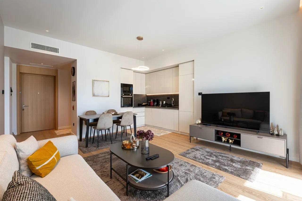 Modernes Wohnzimmer mit Küche in einer Wohnung, Porto Montenegro, Tivat, Montenegro: helles Interieur, Möbel und TV-Bereich.