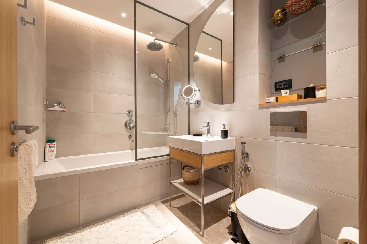 Modernes Badezimmer in einer Wohnung in Porto Montenegro, Tivat, Montenegro: helle Fliesen, Badewanne mit Glasabtrennung, Dusche.