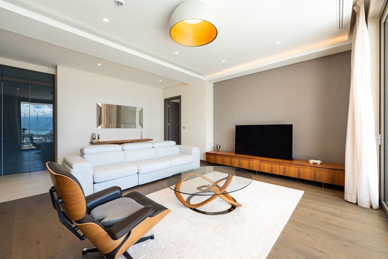 Modern living room in an apartment in Portonovi, Kumbor, Montenegro: white sofa, designer armchair, and marina view.