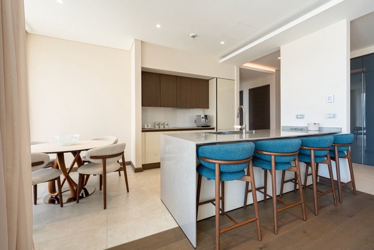 Modern kitchen-living room with an island and blue bar stools in the Portonovi apartments, Kumbor, Montenegro.