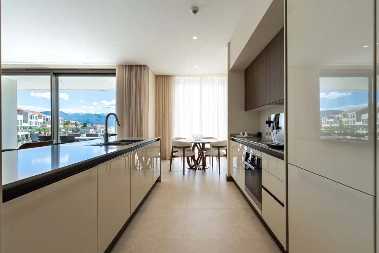 Moderne Küche in der Wohnung Portonovi, Kumbor, Montenegro: Hochglanzfronten, Essbereich und Blick auf den Yachthafen.