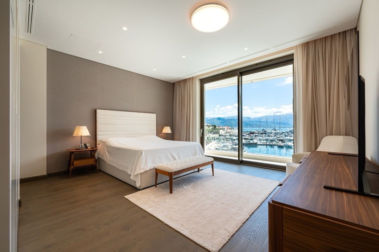 Modern bedroom in Portonovi, Kumbor, Montenegro with panoramic marina views, a double bed, and wooden furniture.