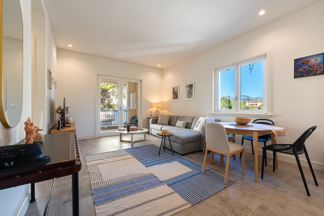 Modernes Wohnzimmer mit grauem Sofa und Essbereich in einer Wohnung in Luštica Bay, Tivat, Montenegro.