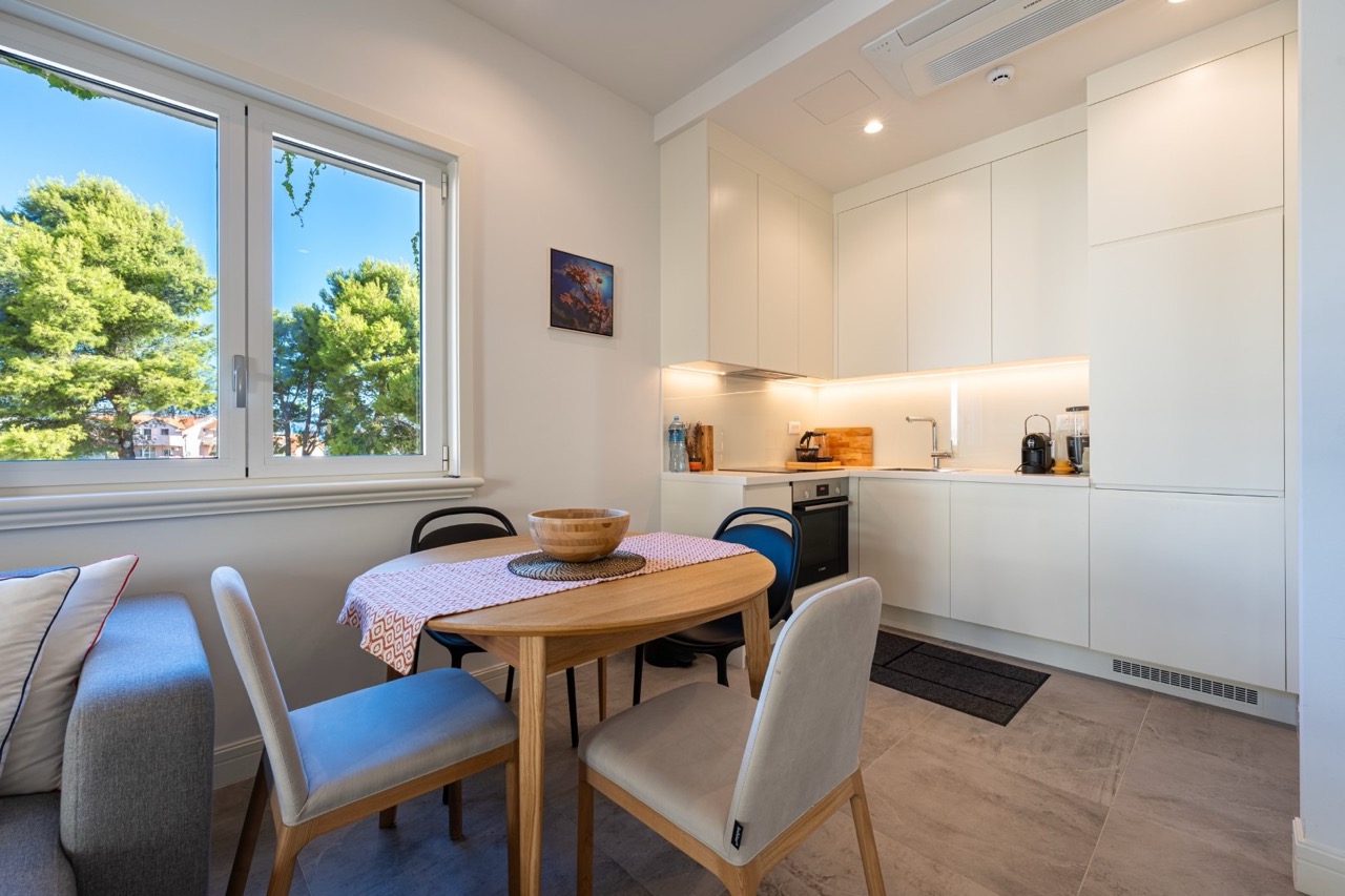Moderne Wohnküche in den Apartments von Luštica Bay, Tivat, Montenegro: helle Einbauküche, Essbereich und Blick auf den Garten.