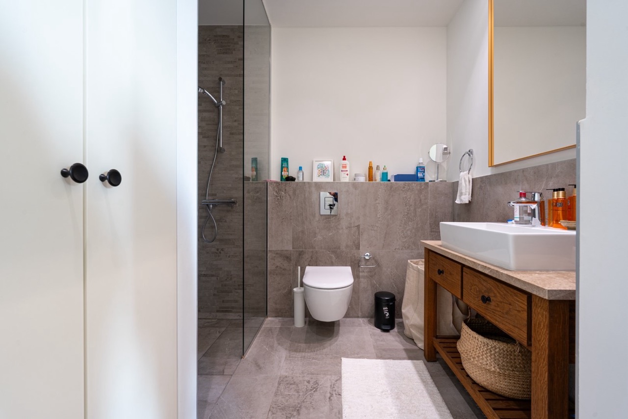 Modernes Badezimmer in einer Wohnung in Luštica Bay, Tivat, Montenegro: Duschkabine, Holzwaschtisch und Fliesen.
