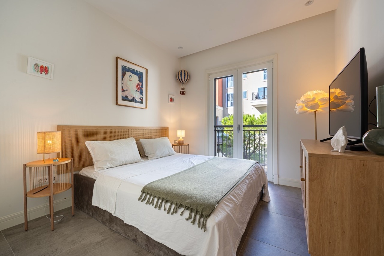 Gemütliches Schlafzimmer in der Wohnung Lustica Bay, Tivat, Montenegro: Doppelbett, geflochtenes Kopfteil und Zugang zum Balkon.