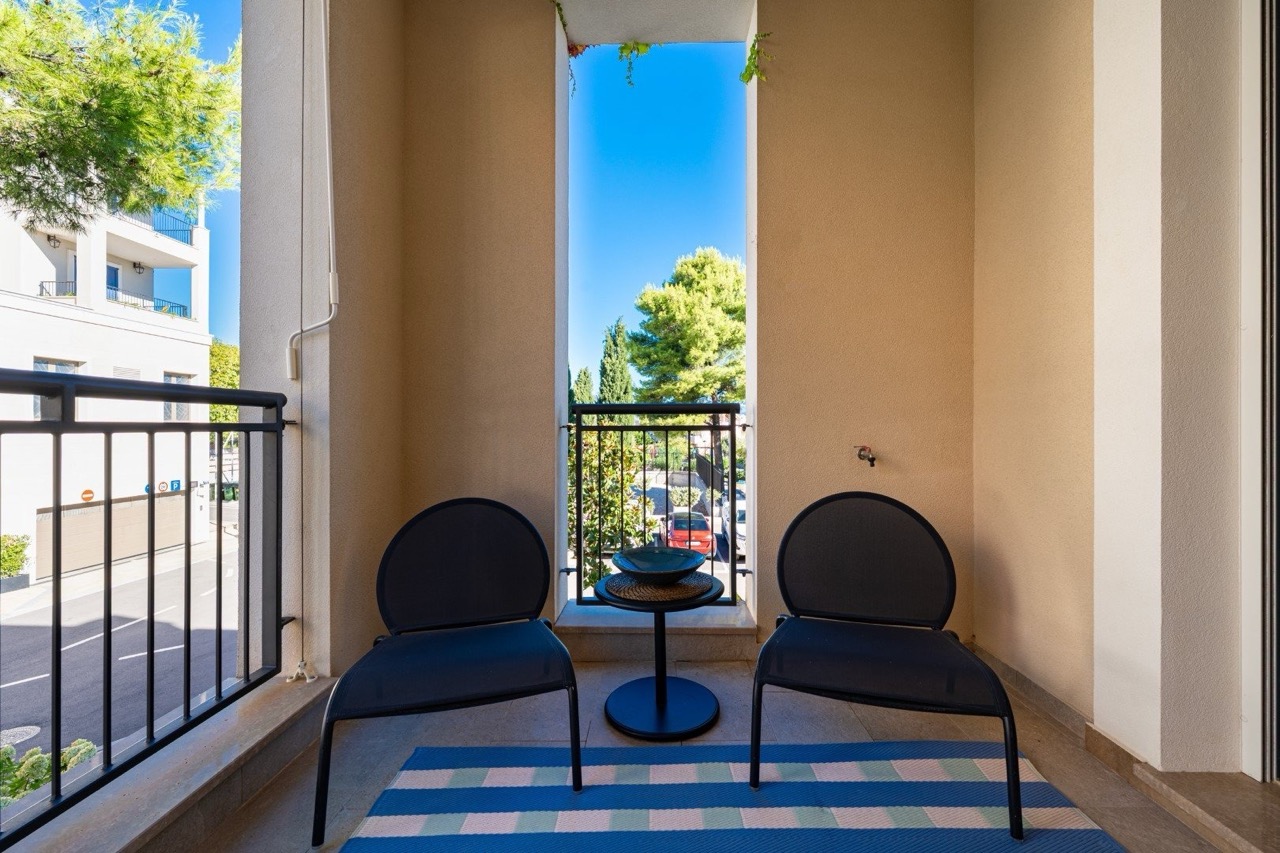 Gemütlicher Balkon mit Möbeln in den Apartments von Luštica Bay, Tivat, Montenegro: Blick ins Grüne und auf die Straße in einer modernen Wohnanlage.