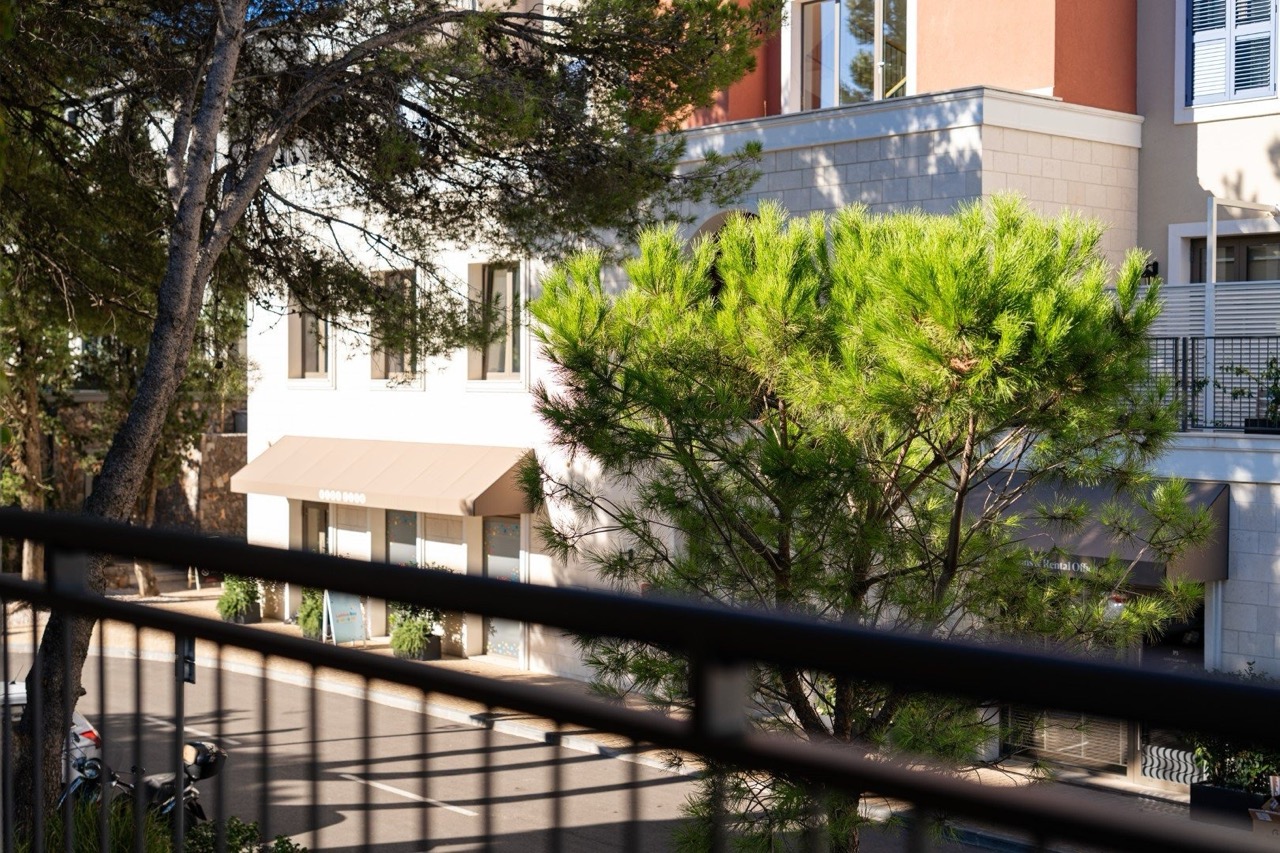 Blick vom Balkon der Apartments in Luštica Bay, Tivat, Montenegro: modernes Gebäude mit Steinverkleidung und grüne Kiefer.