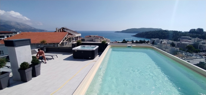 Terrace with a pool and jacuzzi on the roof of a house in Becici, Montenegro, with panoramic views of the Adriatic Sea.