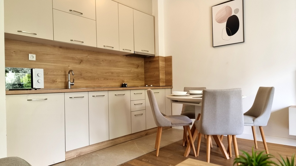 Modern kitchen with light-colored furniture and a dining area in an apartment in Bečići, Montenegro. Scandinavian-style interior.