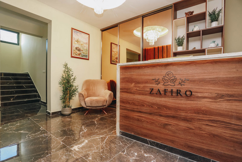 Reception desk at the Zafiro hotel, Bečići, Montenegro: marble floor, an armchair, and a staircase in a modern interior.