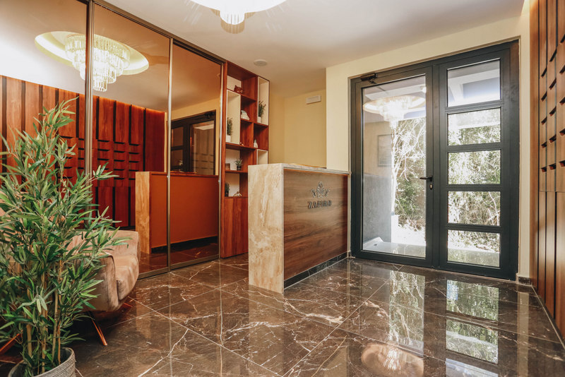 Modern reception desk in the lobby of a residential complex in Becici, Montenegro: marble floor, wood finishes, and decor.
