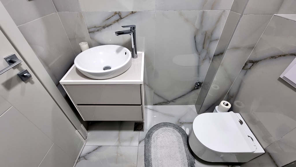 Modern bathroom in an apartment, Becici, Montenegro: light marble-look tiles, wall-mounted vanity, and sanitary ware.
