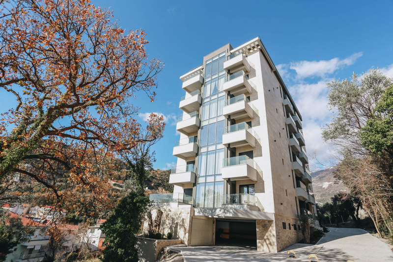 Modern residential complex with panoramic windows and balconies in Bečići, Montenegro, exterior view of the building.