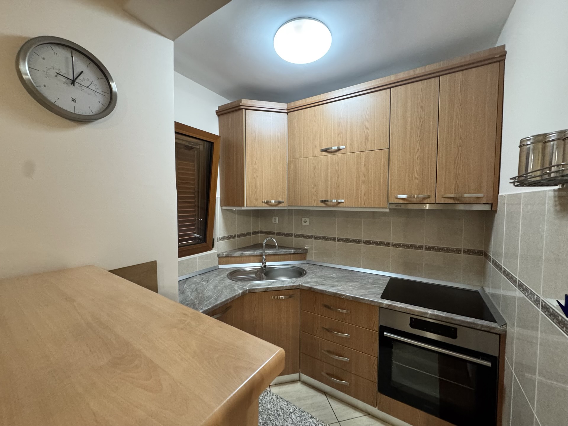 Eckküche mit Holzfronten und Einbaugeräten in einer Wohnung, Stadt Budva, Montenegro.