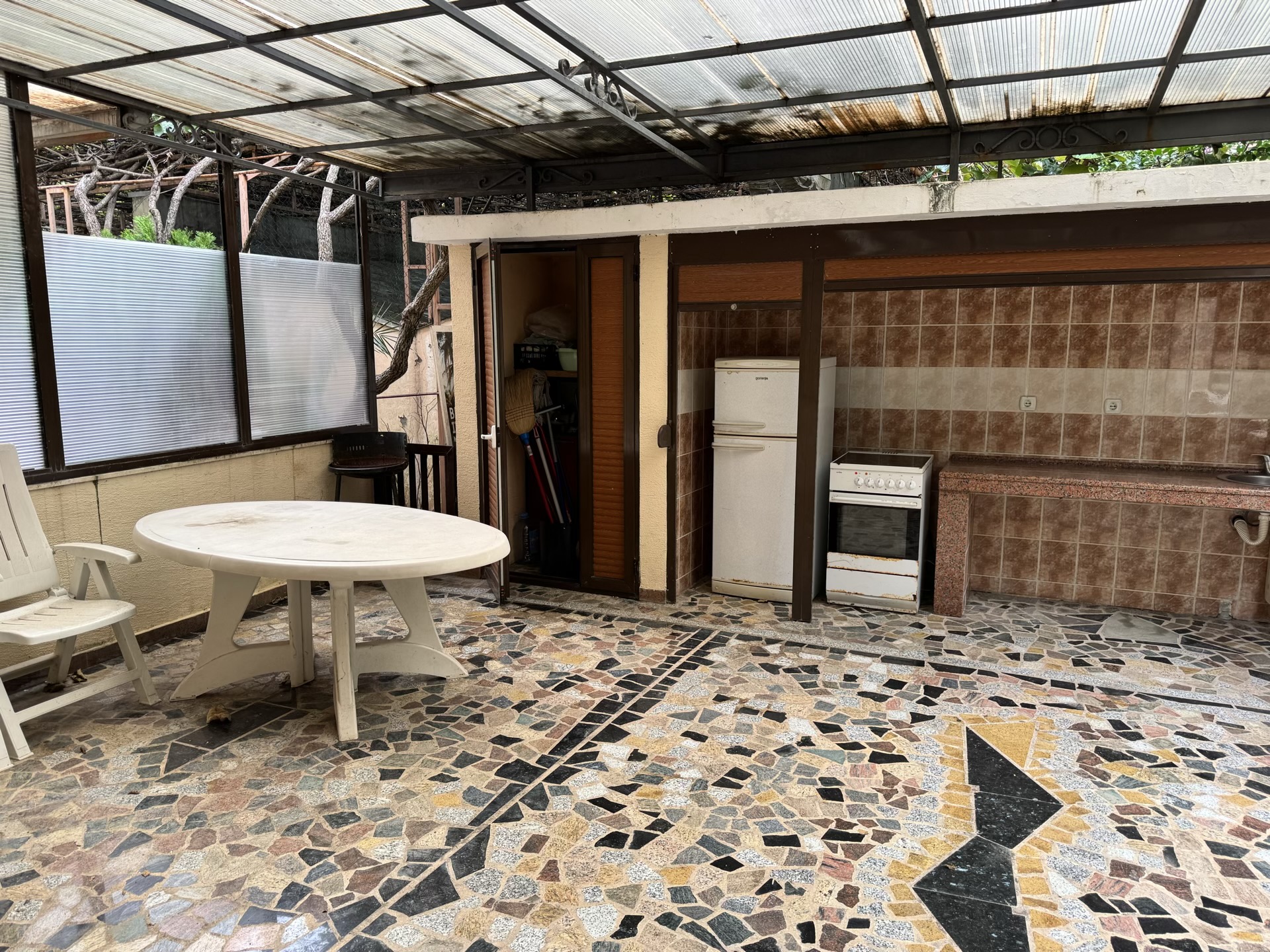 Sommerküche auf der Terrasse mit Herd, Kühlschrank und Essbereich in der Wohnung, Budva, Montenegro.