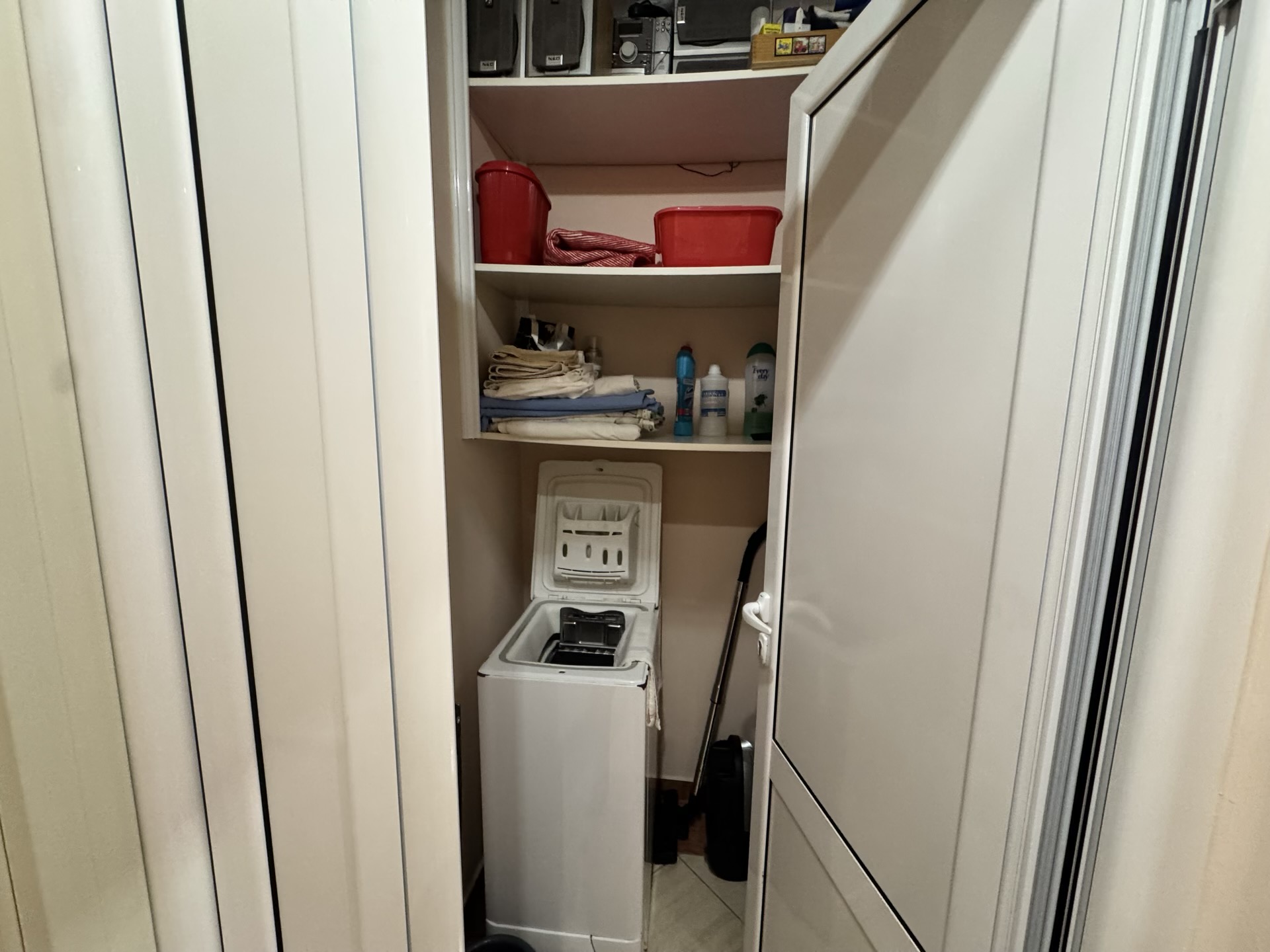 Hauswirtschaftsnische mit Toplader-Waschmaschine und Regalen zur Aufbewahrung in einer Wohnung, Budva, Montenegro