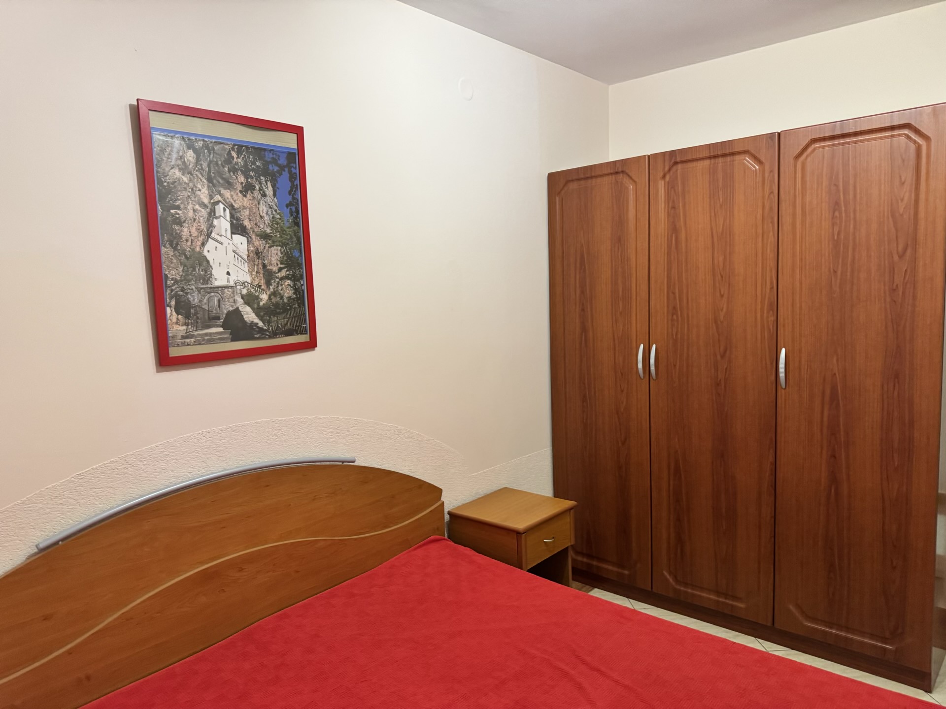 Schlafzimmer in einer Wohnung in Budva, Montenegro: Doppelbett, Holzschrank und ein Bild des Klosters Ostrog.
