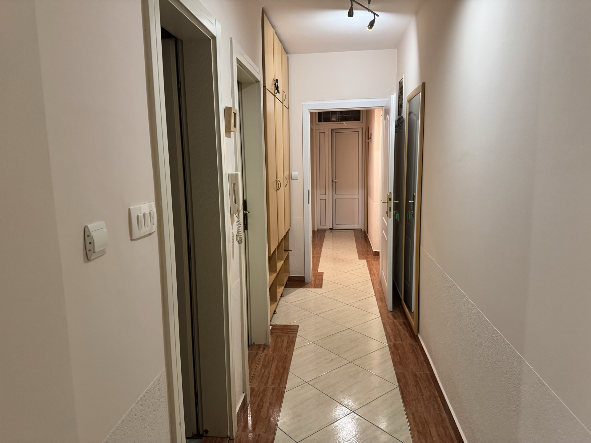 Heller Flur in einer Wohnung in Budva, Montenegro: Einbauschrank, Fliesenboden und Innentüren.