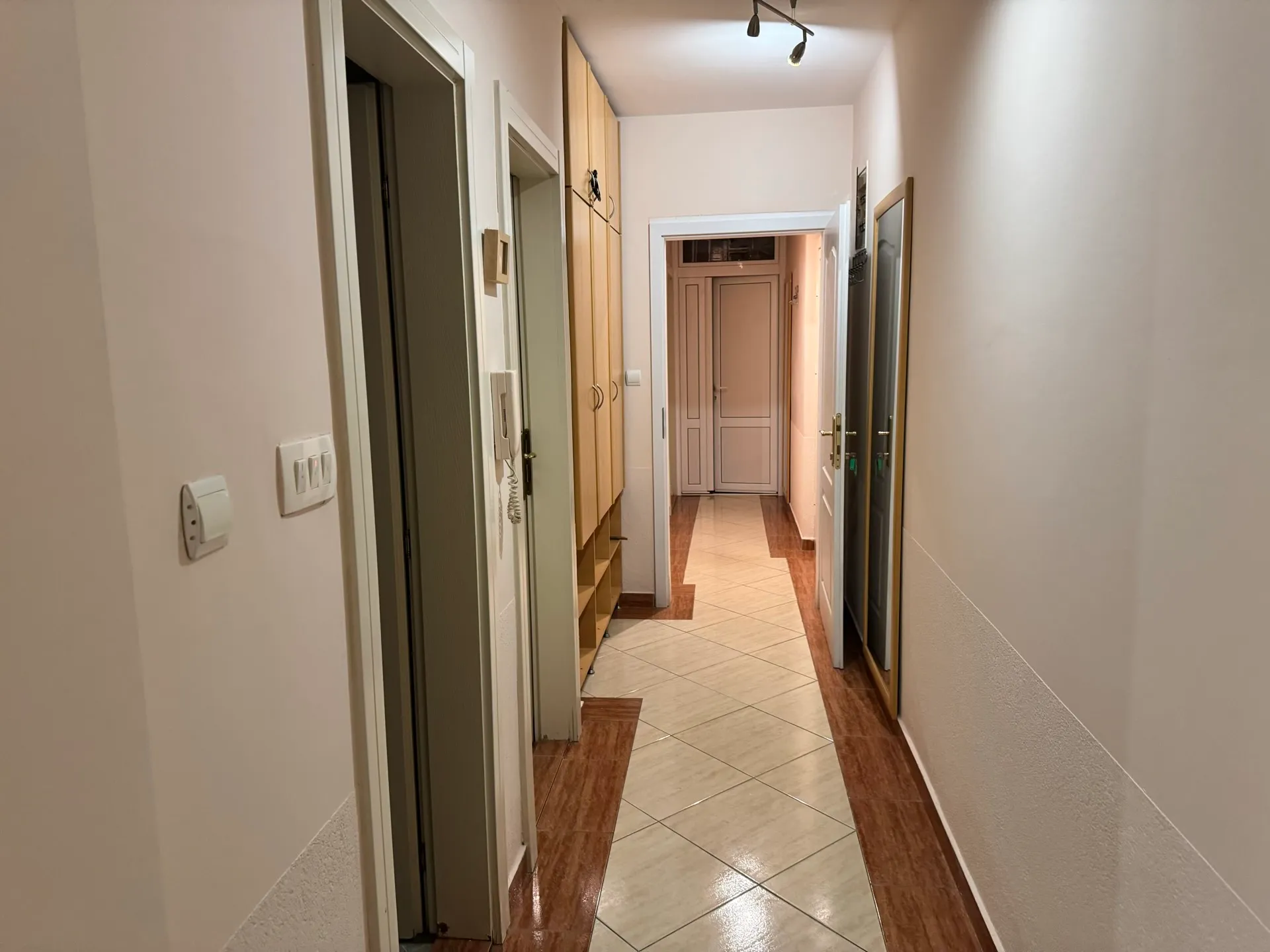 Bright hallway in an apartment in Budva, Montenegro: built-in wardrobe, tiled floor, and interior doors.