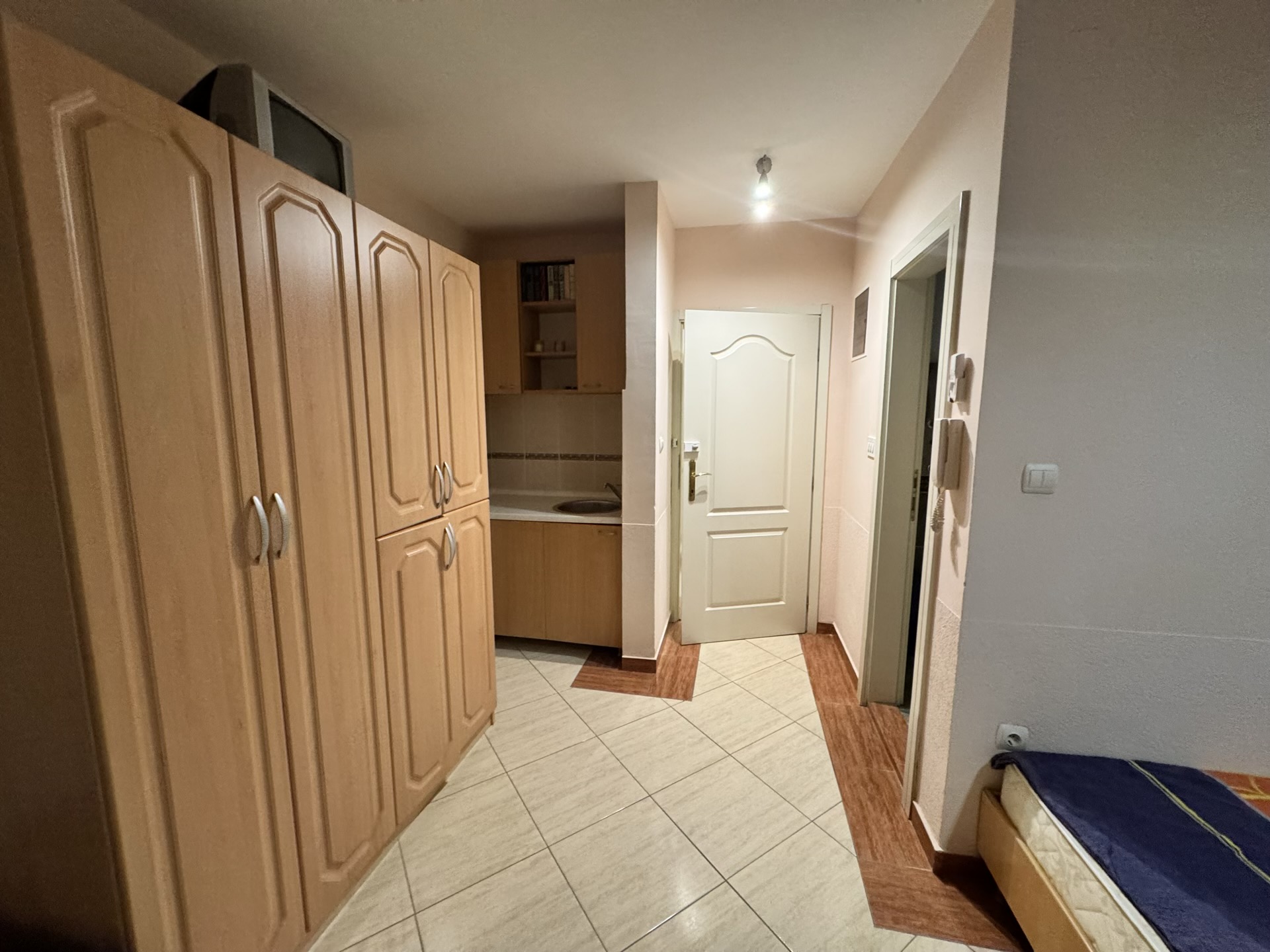 Kompakte Küche in einer Wohnung in Budva, Montenegro: helle Einbauküche, Einbauschrank und Fliesenboden im Flur.