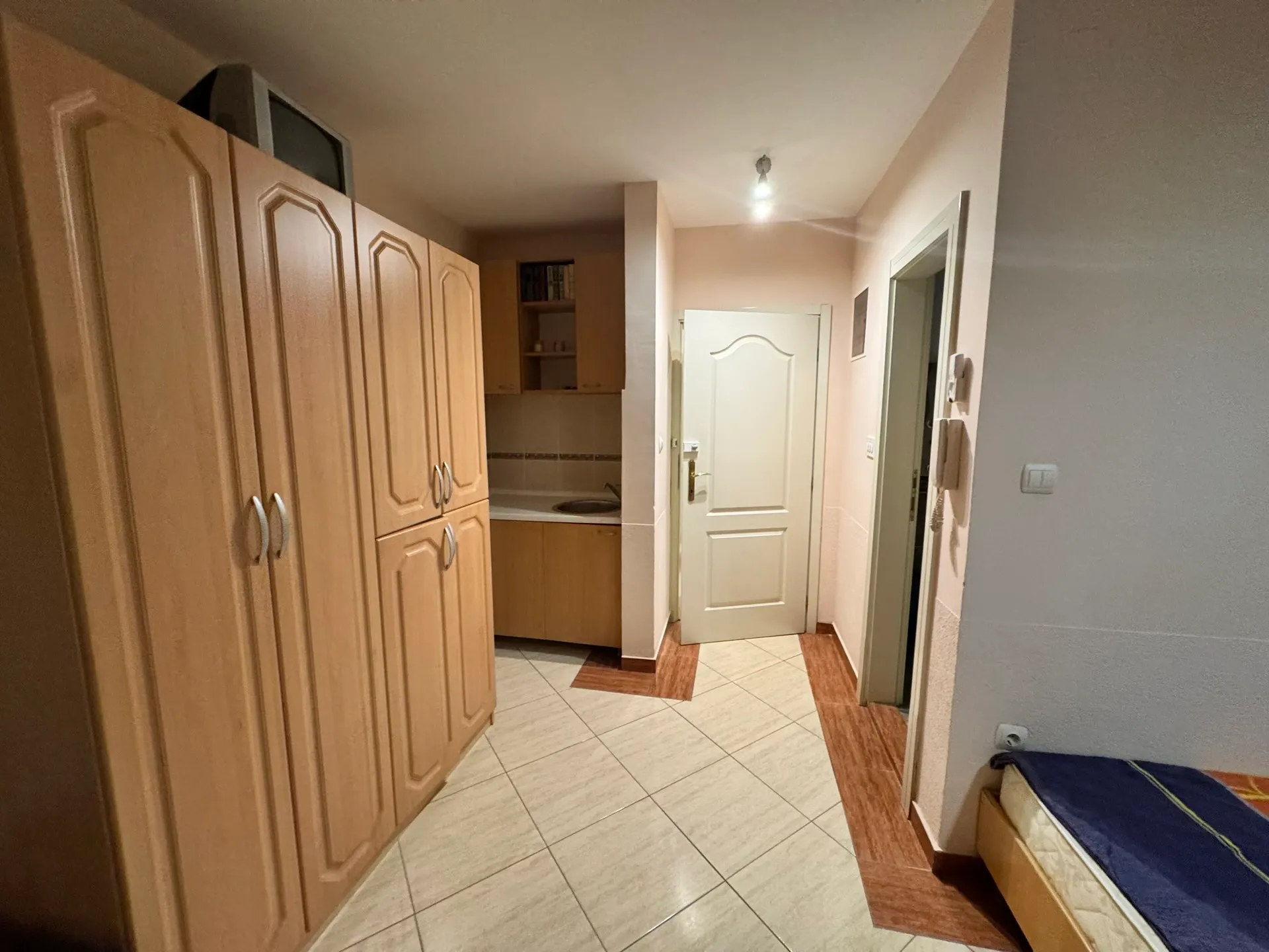 Compact kitchen in an apartment in Budva, Montenegro: light-colored cabinets, built-in wardrobe, and tiled hallway floor.